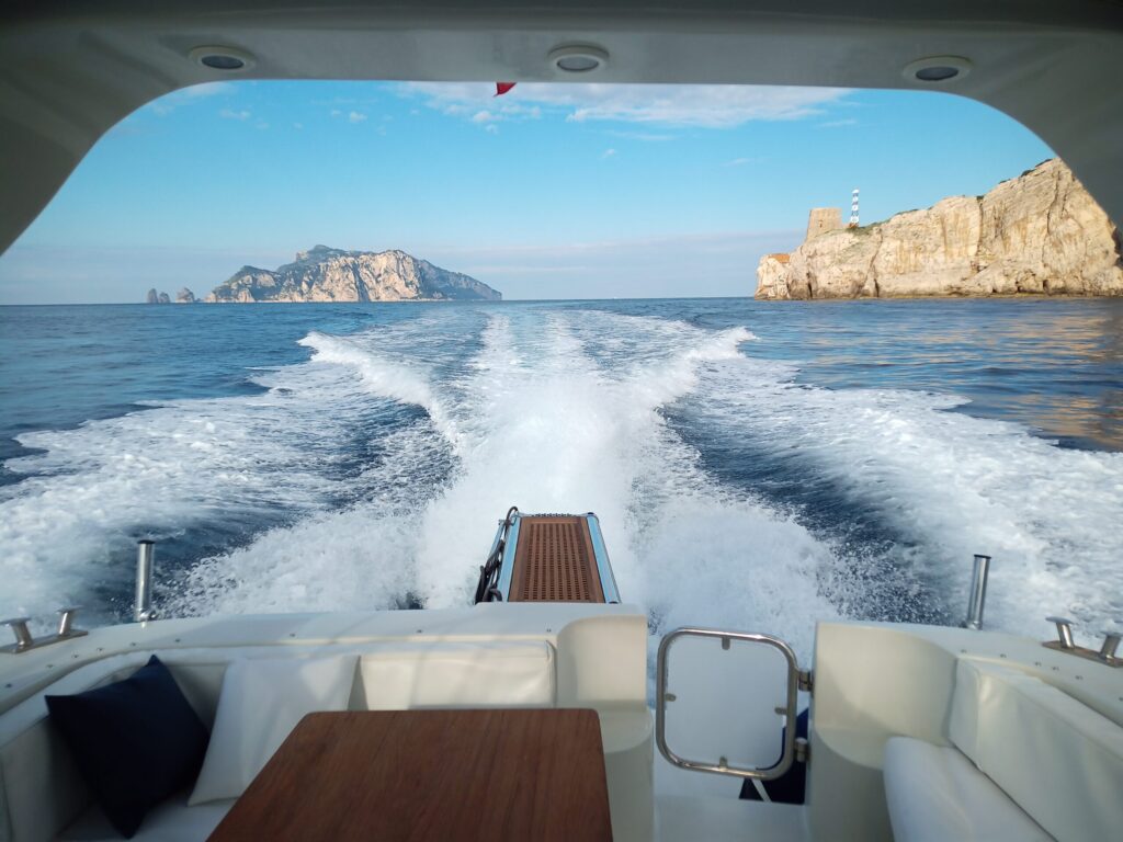 View from the back of a yacht, showcasing a small island and white water as the yacht sails